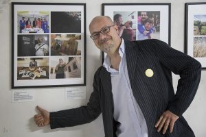 Luca Zampini davanti al pannello delle fotografie sulle attività dell'Uici Ferrara pannello